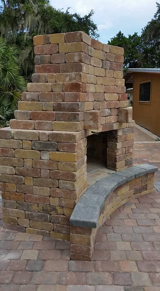 Brick outdoor fireplace with curved seating. Tan, red, and yellow bricks.