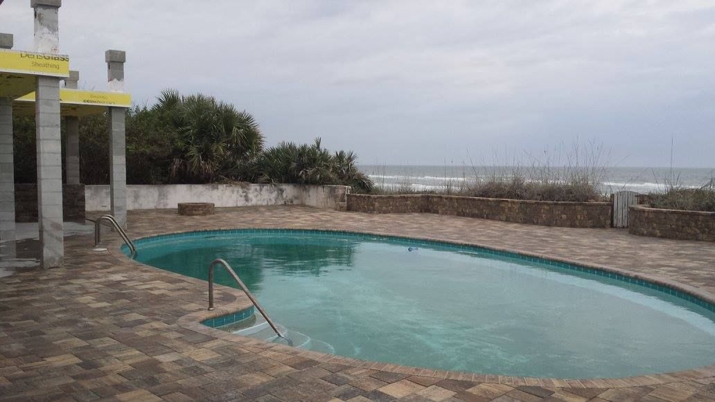 Swimming pool overlooking the ocean under a cloudy sky.