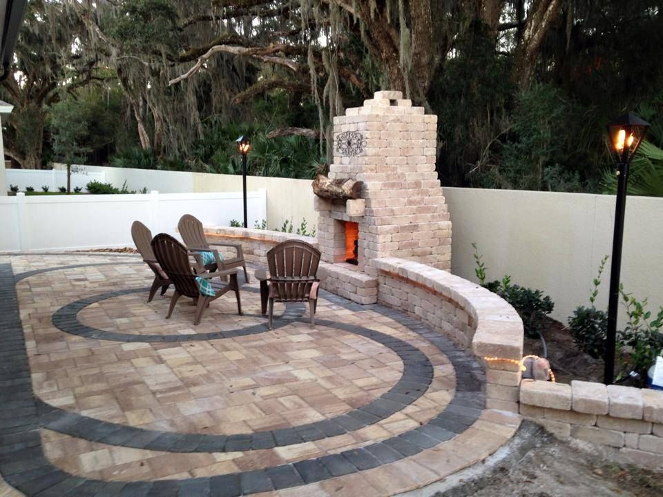 Outdoor brick fireplace with seating area, patio, and lighting.