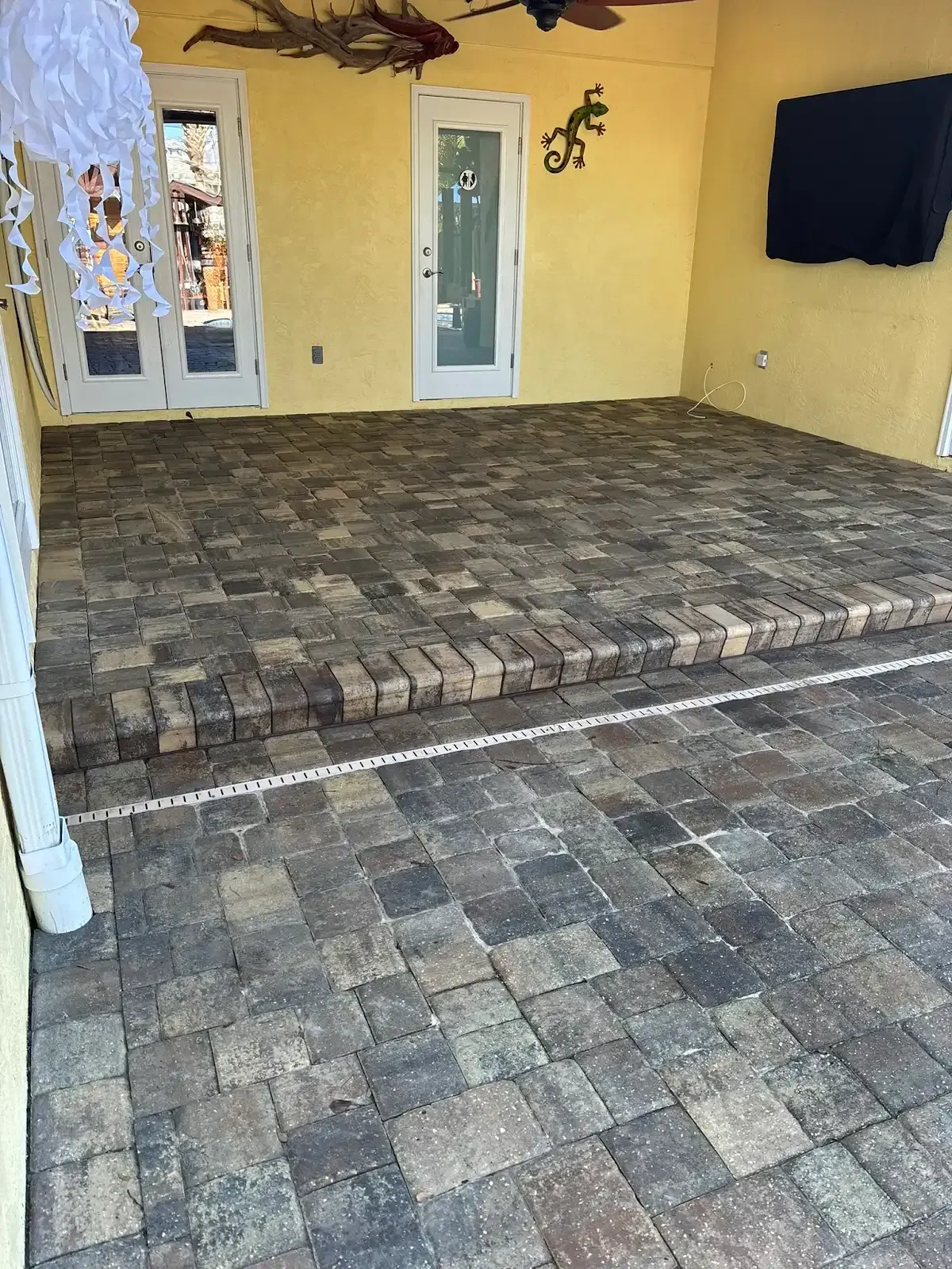 Brick pavers on a patio with a step up to a doorway. Yellow walls and white trim.