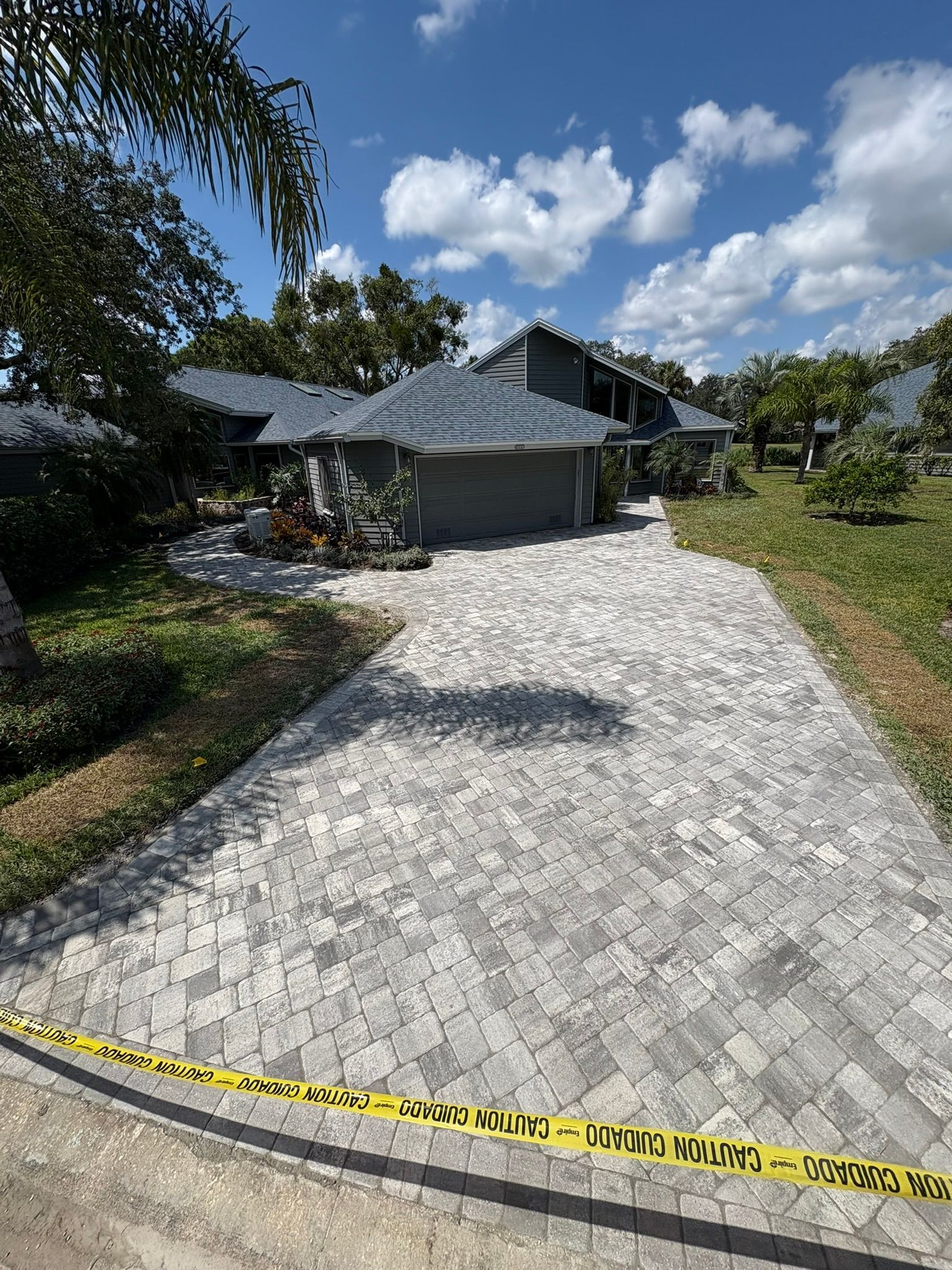 Front view of a dark house with a stone driveway and yellow caution tape across the foreground.