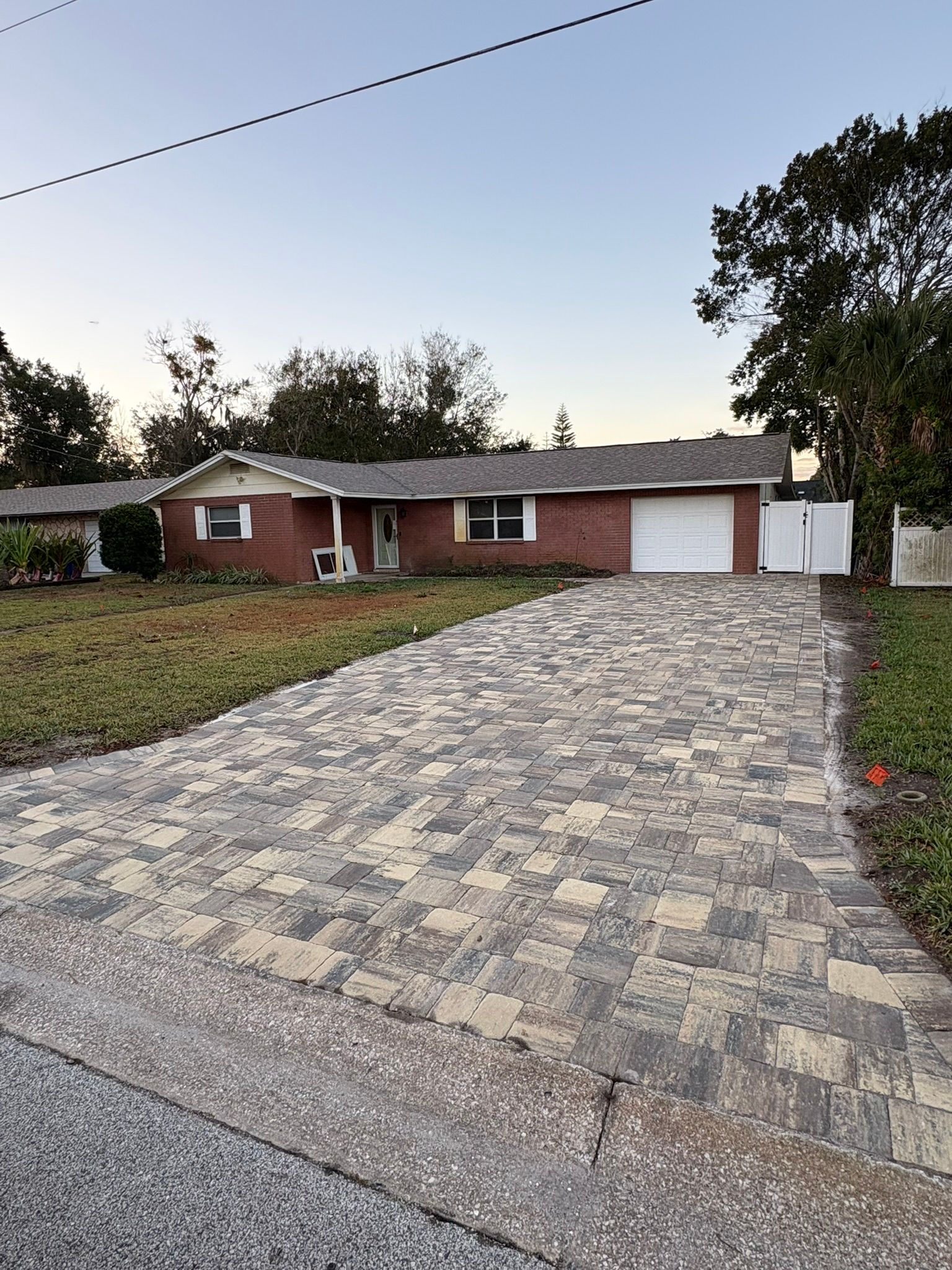 Single-story brick house with a large stone driveway at dusk