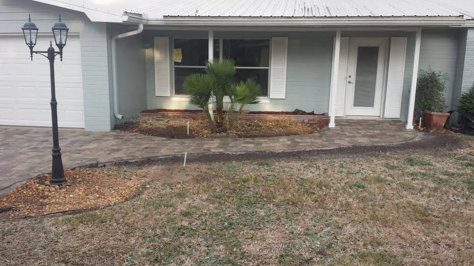 Front of a house with light blue siding and white trim, with a small garden bed and a walkway.