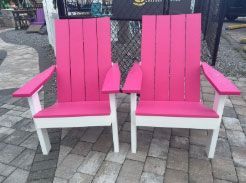 Two bright pink-and-white chairs on a brick patio outdoors