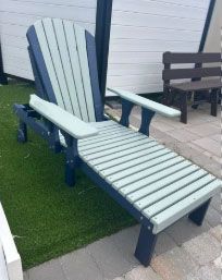 Light gray lounge chair with dark blue legs on artificial grass beside a patio