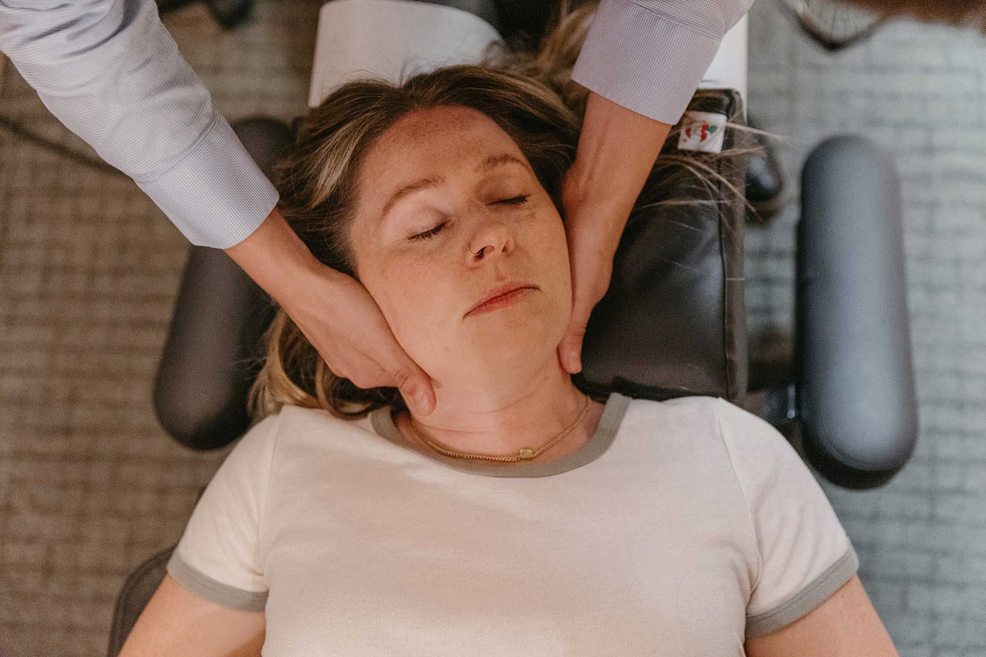Person receiving a neck treatment while lying on a chair
