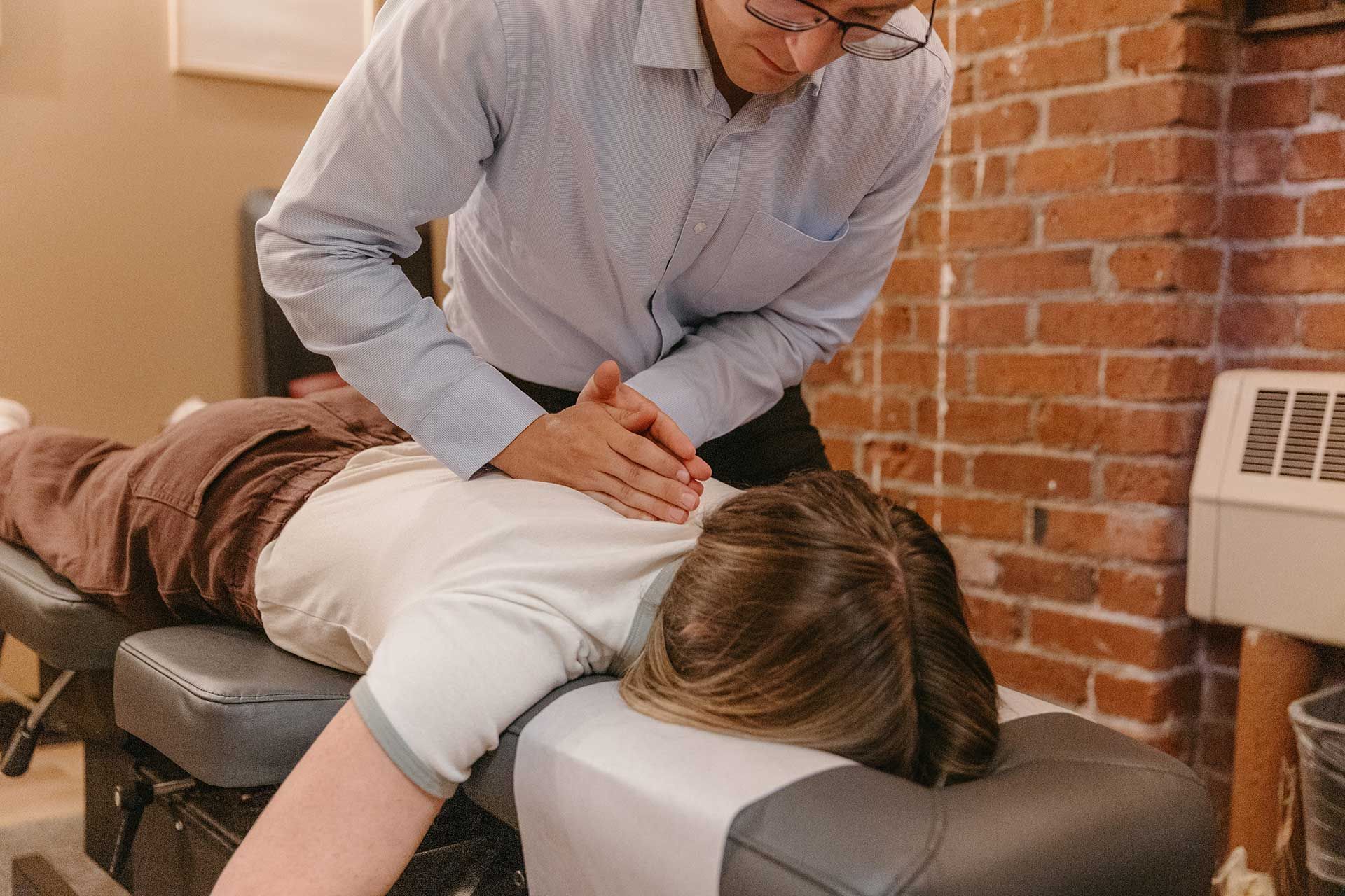 Chiropractor giving a back adjustment to a patient lying face down on a treatment table in a clinic