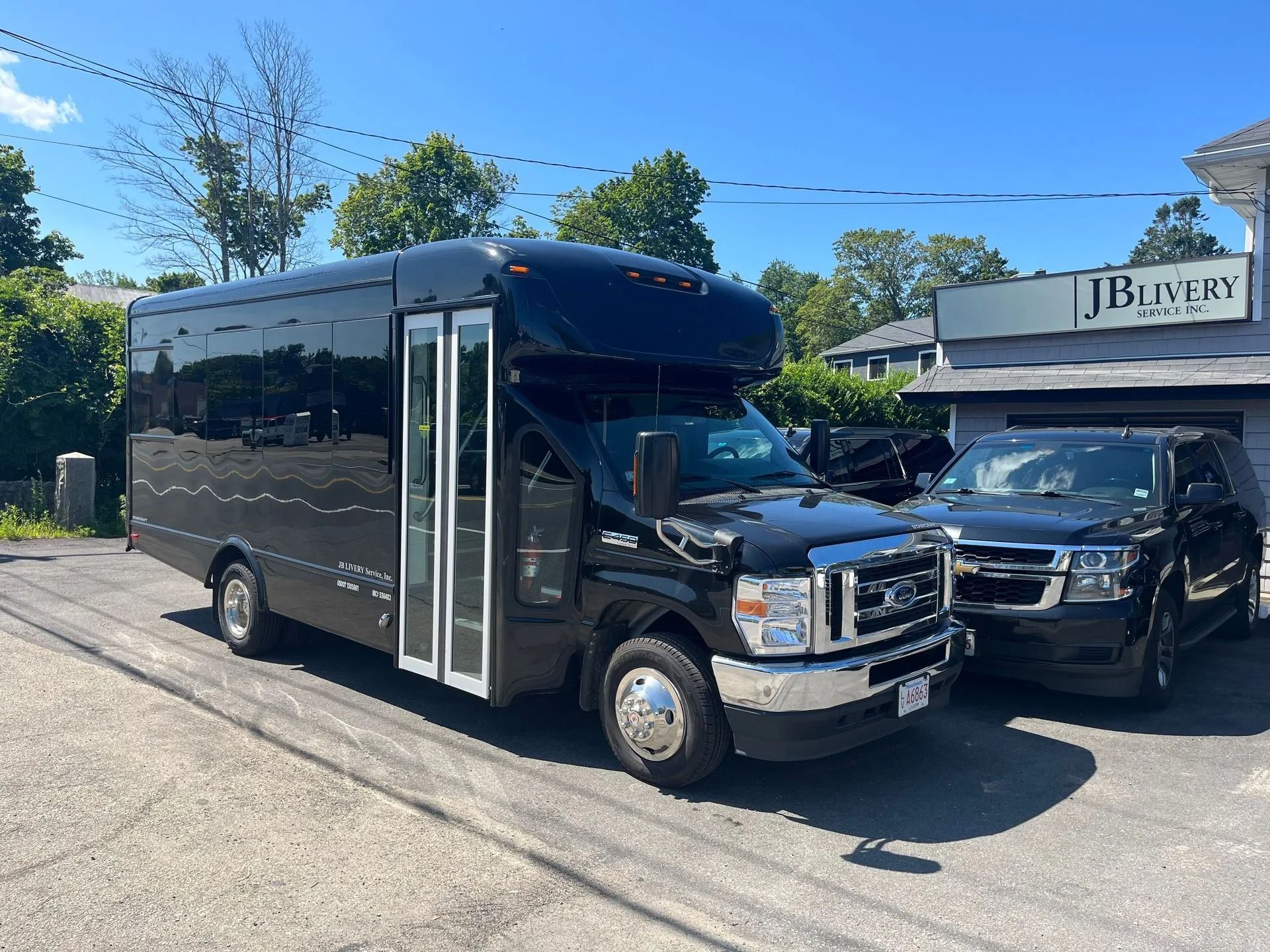 Black passenger bus and SUV parked outside of a building with