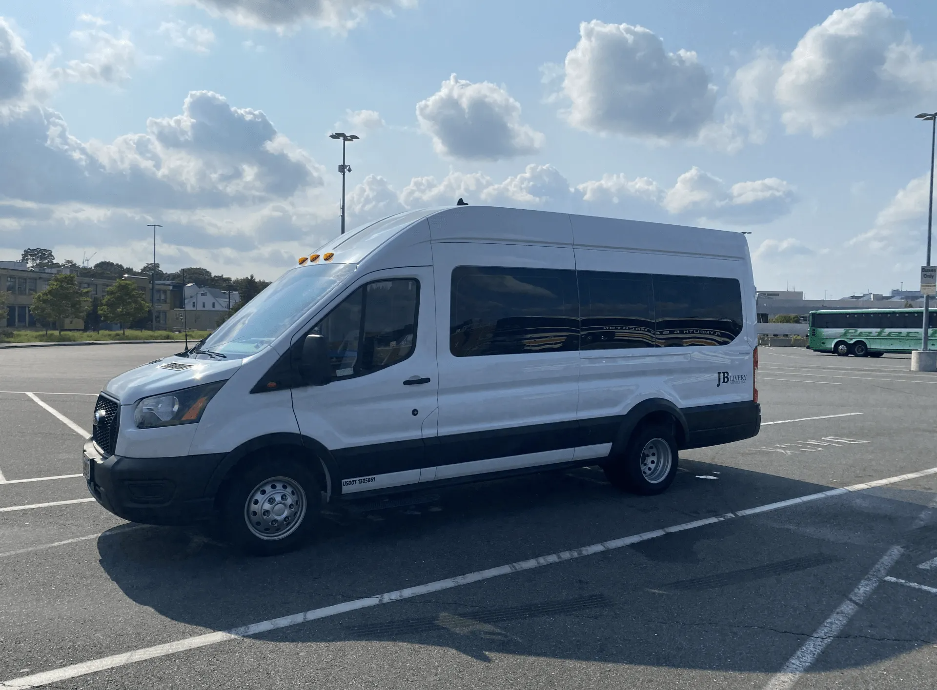 White passenger van parked in a parking lot on a partly cloudy day.