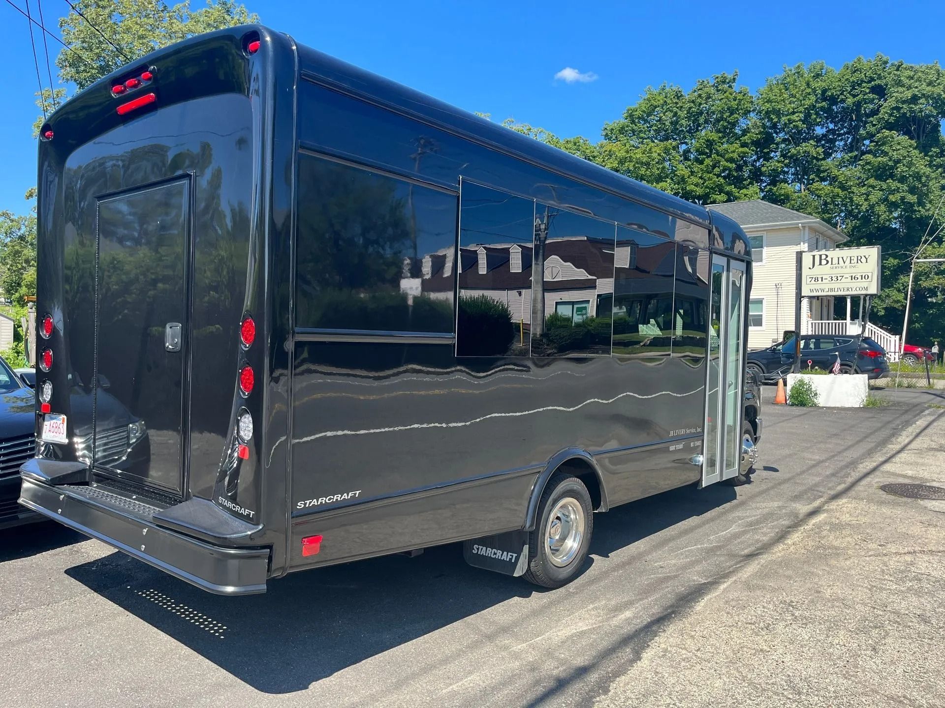 Black passenger bus parked on a street; side view. Sunny day.