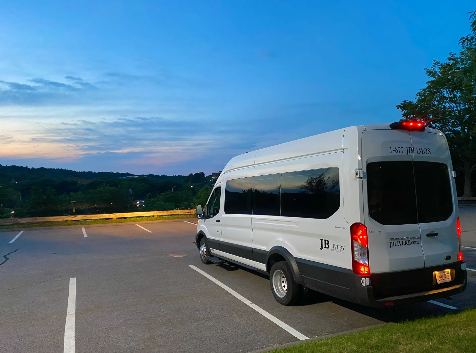 White passenger van parked in a lot with a scenic view in the background at dusk.