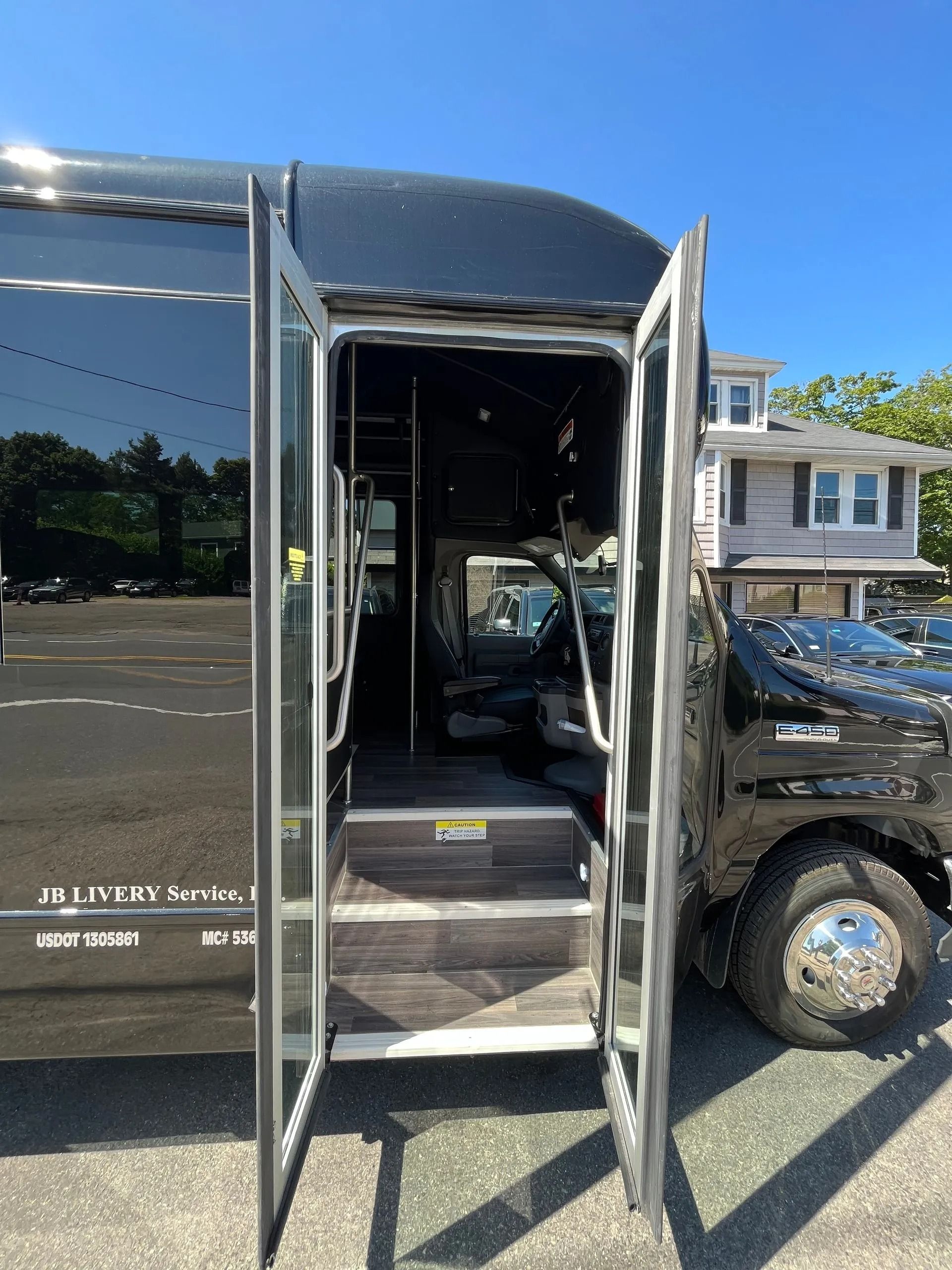 Black bus with open doors revealing interior and steps.