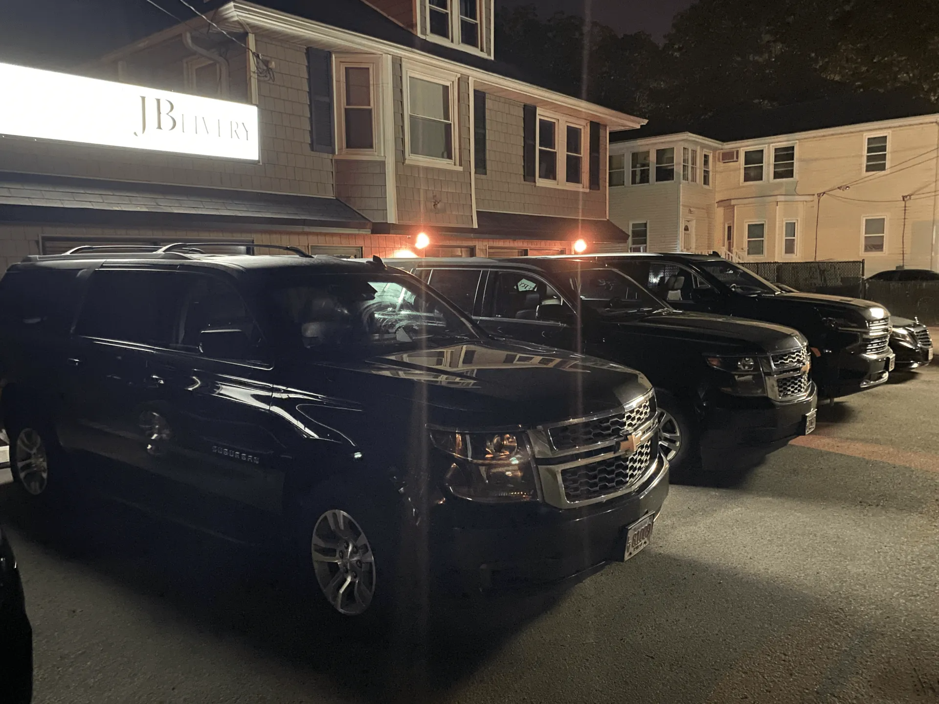 Black SUVs parked in front of a building at night.