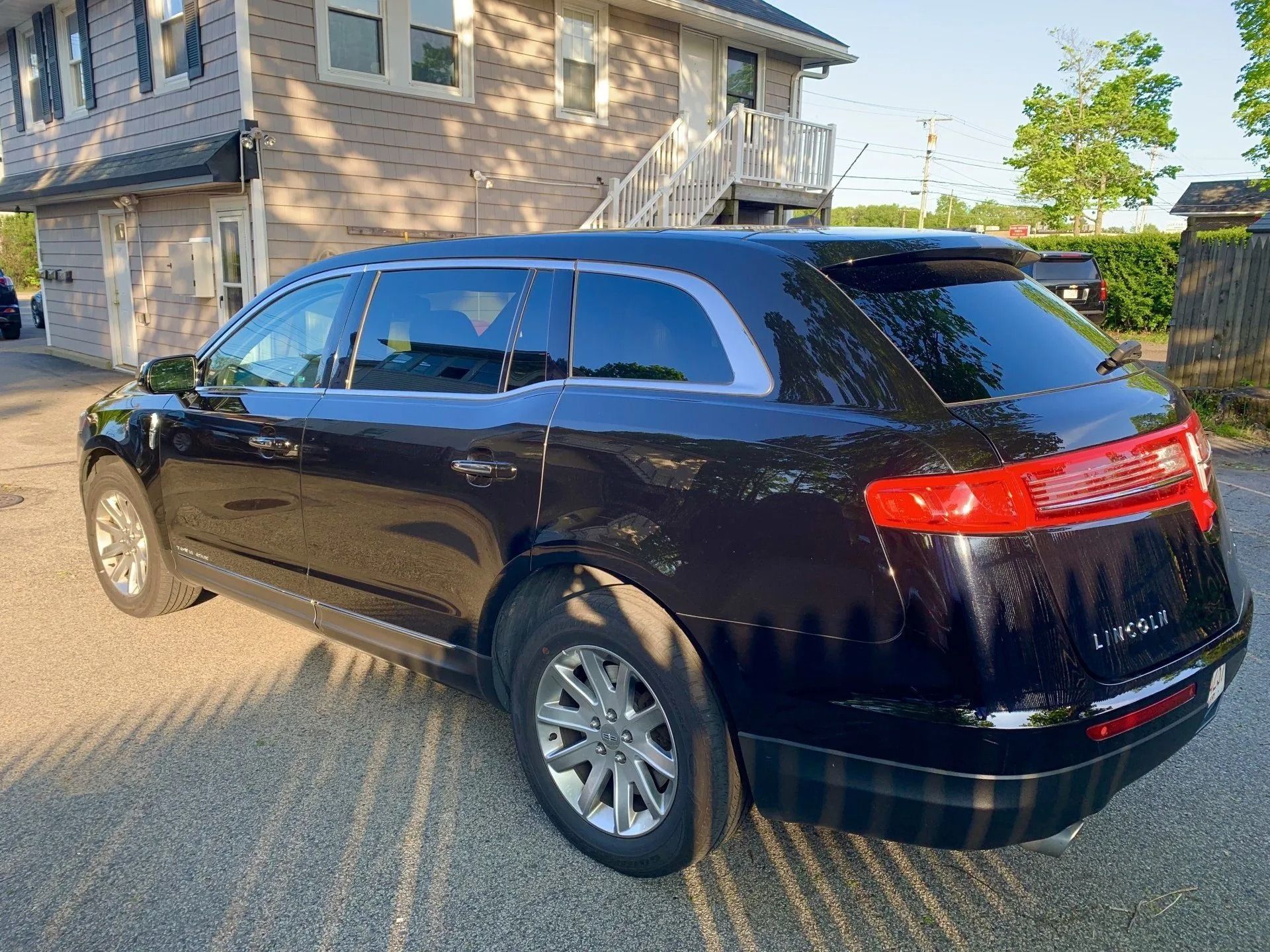 Black Lincoln MKT wagon parked outside a building with trees.