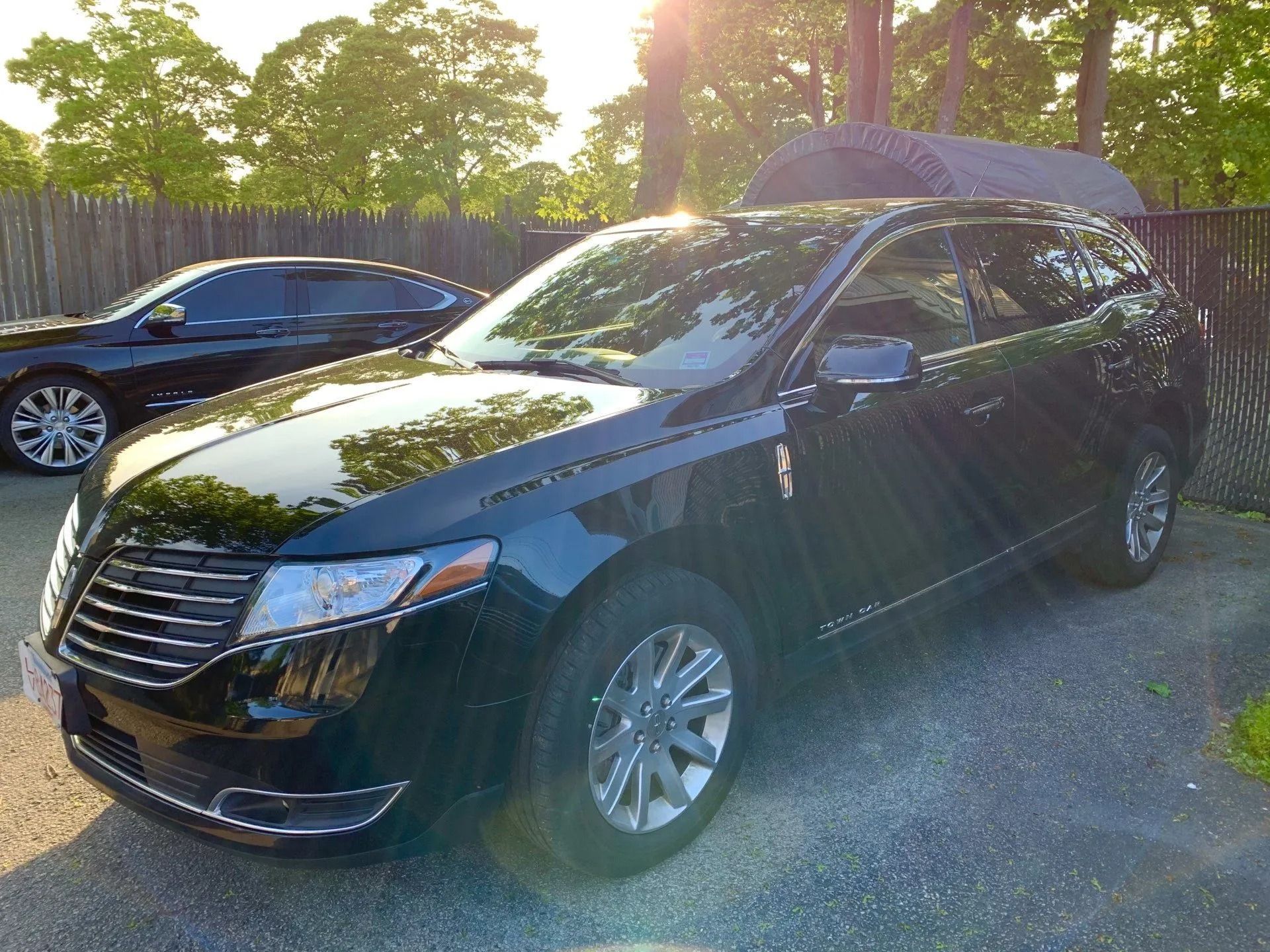 Black Lincoln SUV parked on gravel driveway in front of a fence.