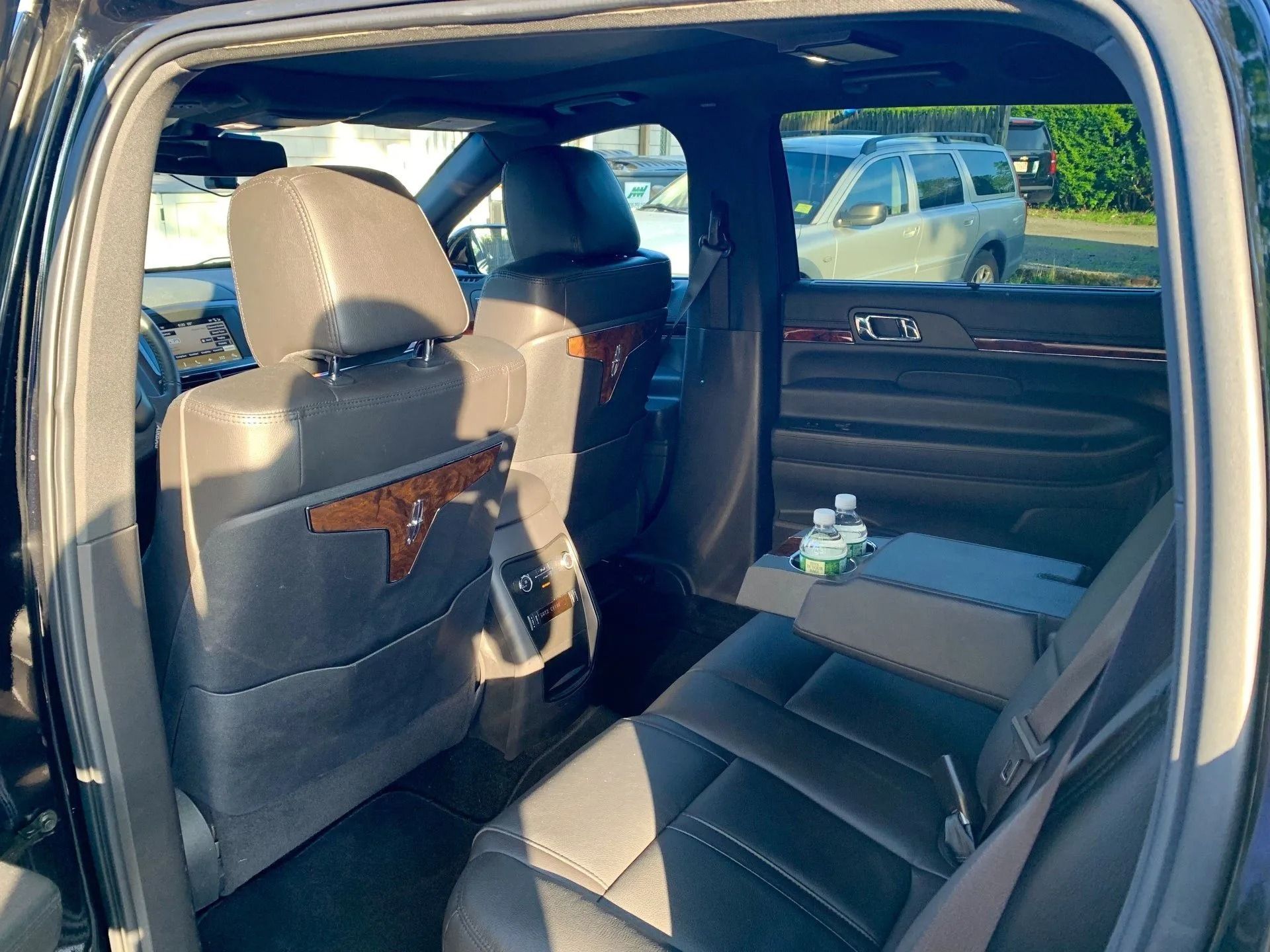 Interior of a black SUV with leather seats; back seats visible, water bottle in the center armrest.