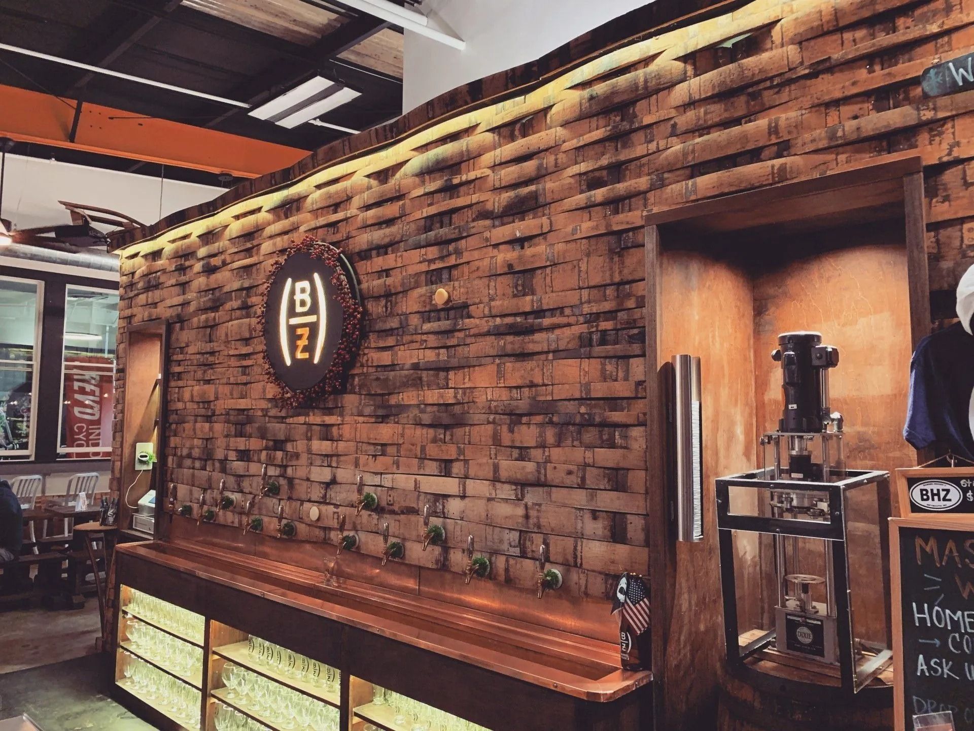Bar with brick wall, taps, and a backlit logo. Interior shot.
