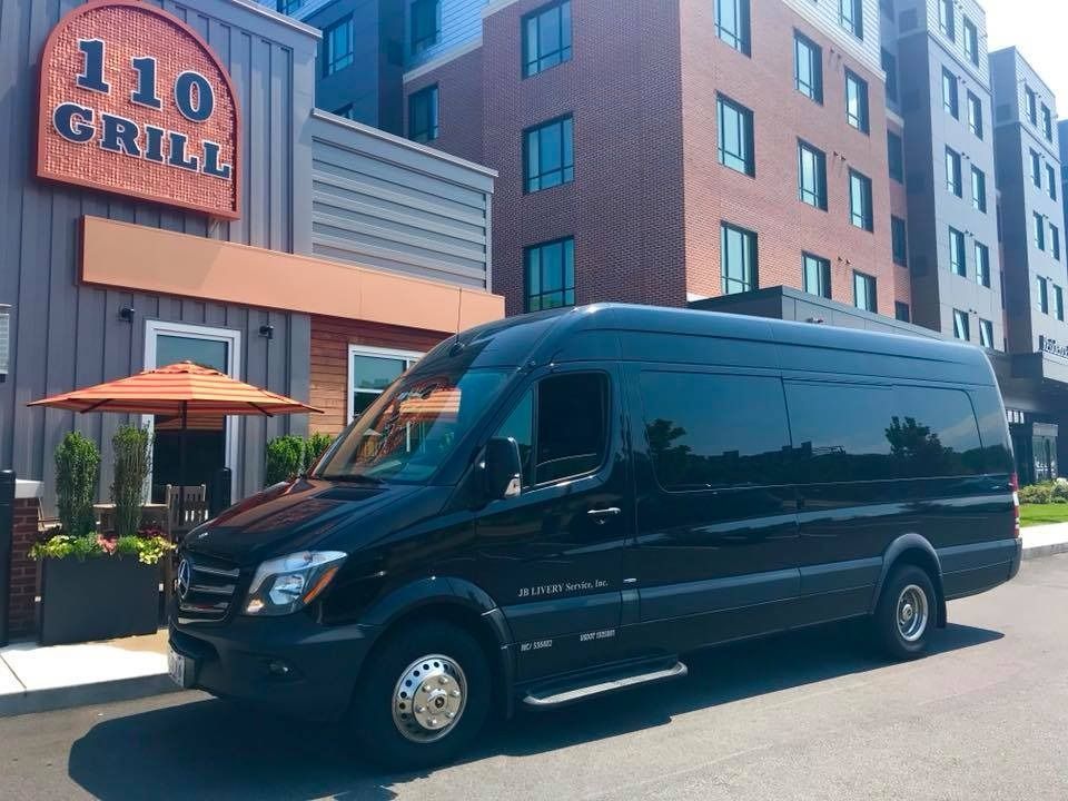 Black van parked in front of 110 Grill restaurant, with modern building in the background.