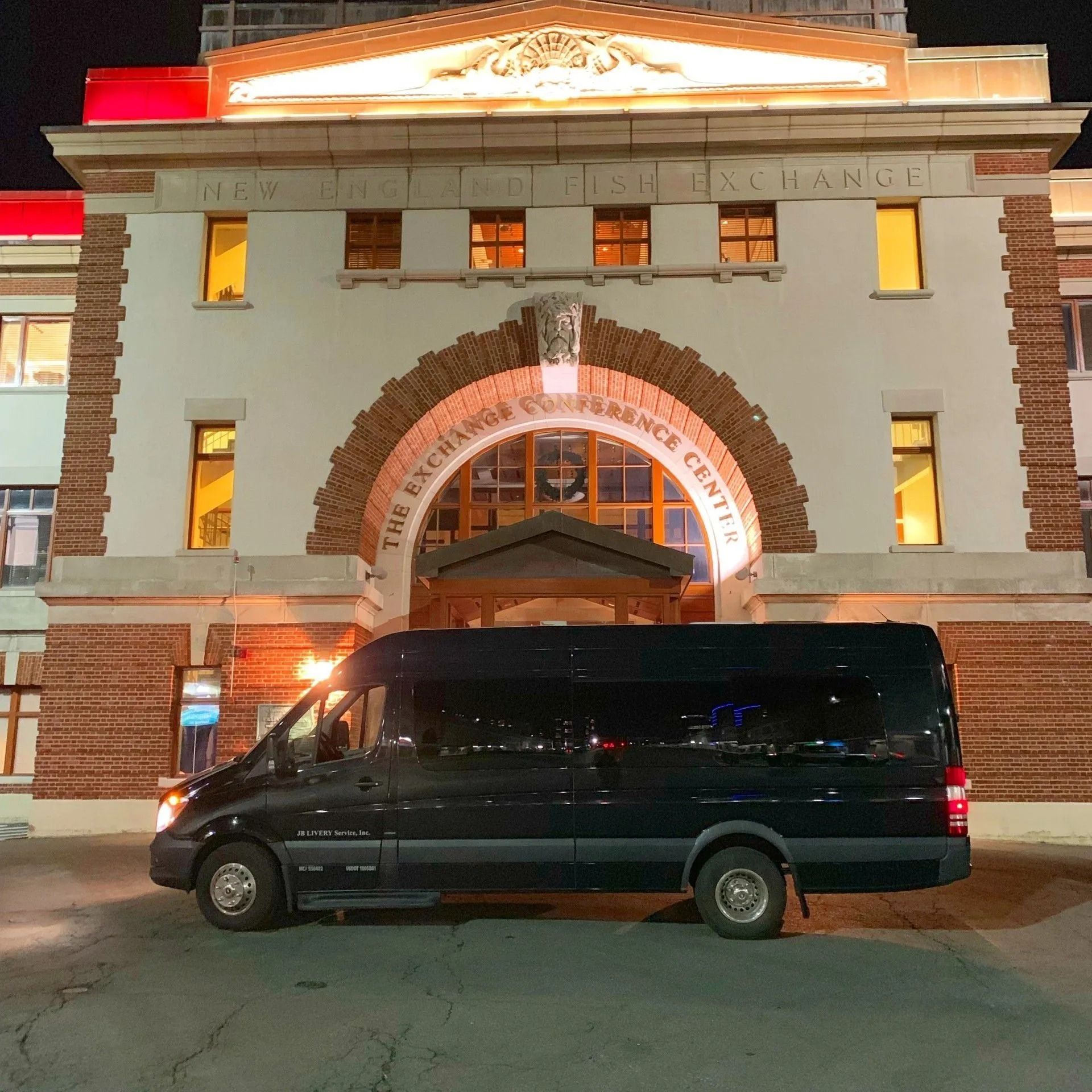 Black van parked in front of a lit-up building at night. The building's sign reads