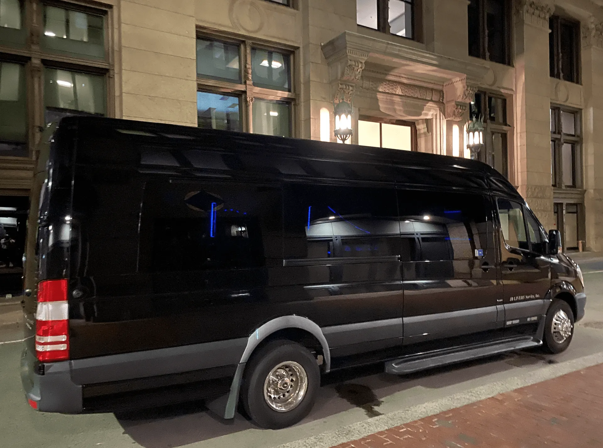 Black van parked in front of a building with ornate architecture at night.