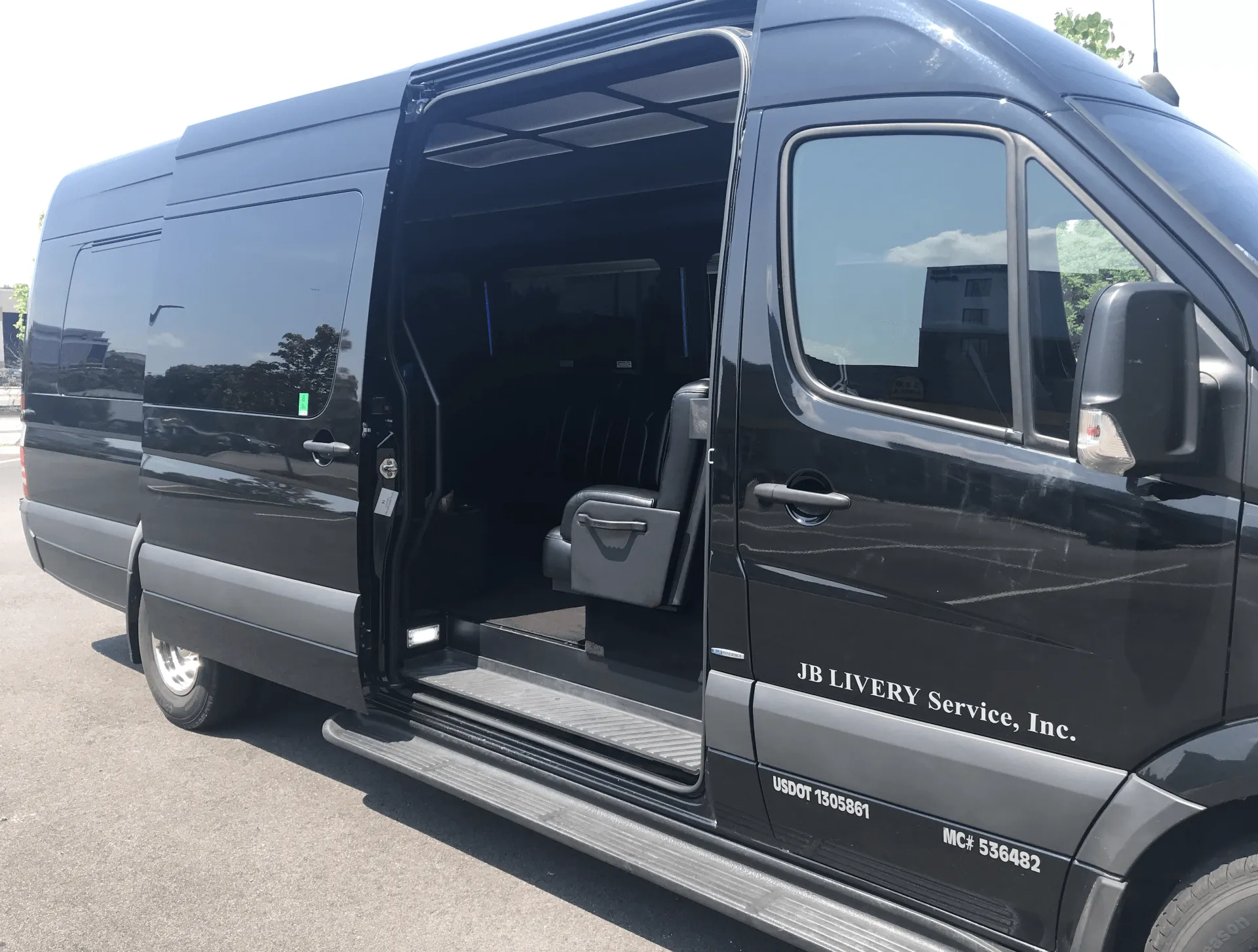 Black passenger van with sliding door open, parked on pavement.