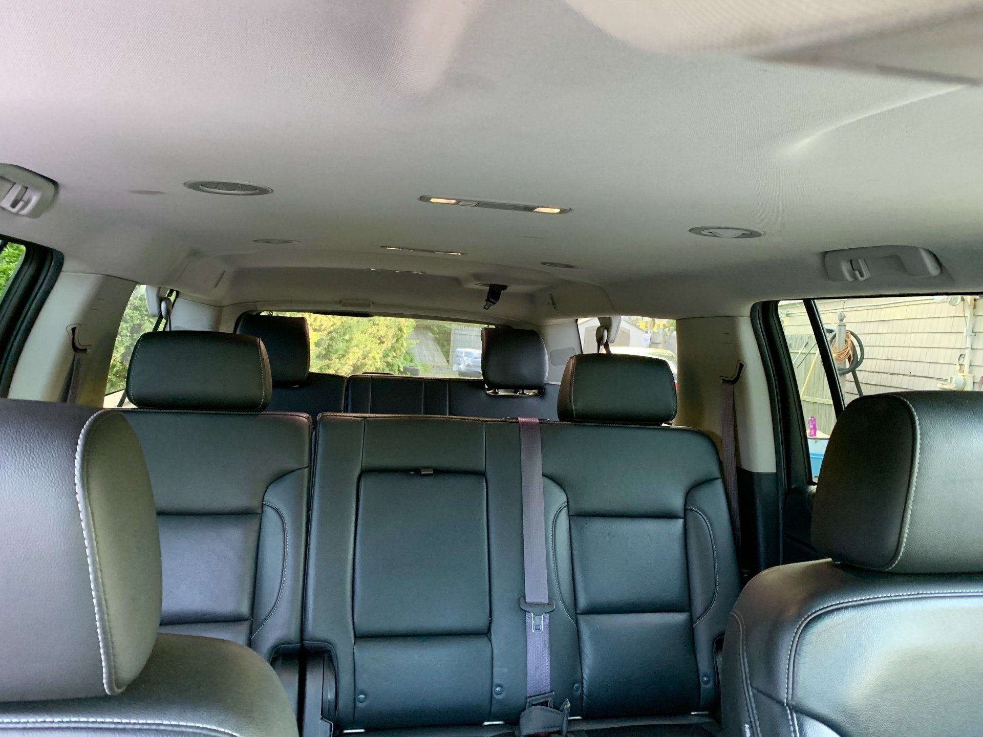 Interior view of a black leather SUV, showing rear seats, headrests, and ceiling lights.