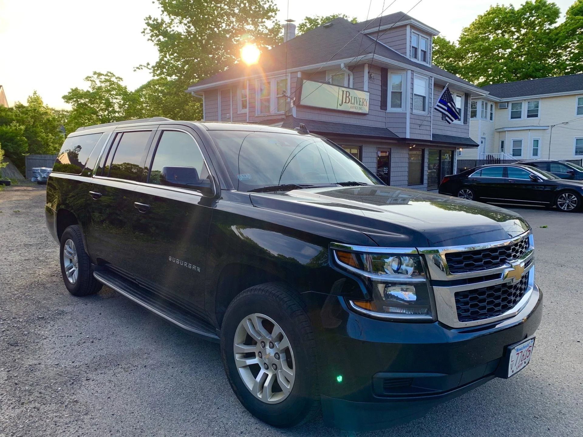 Black SUV parked in front of a two-story building with a restaurant. Bright sunlight.