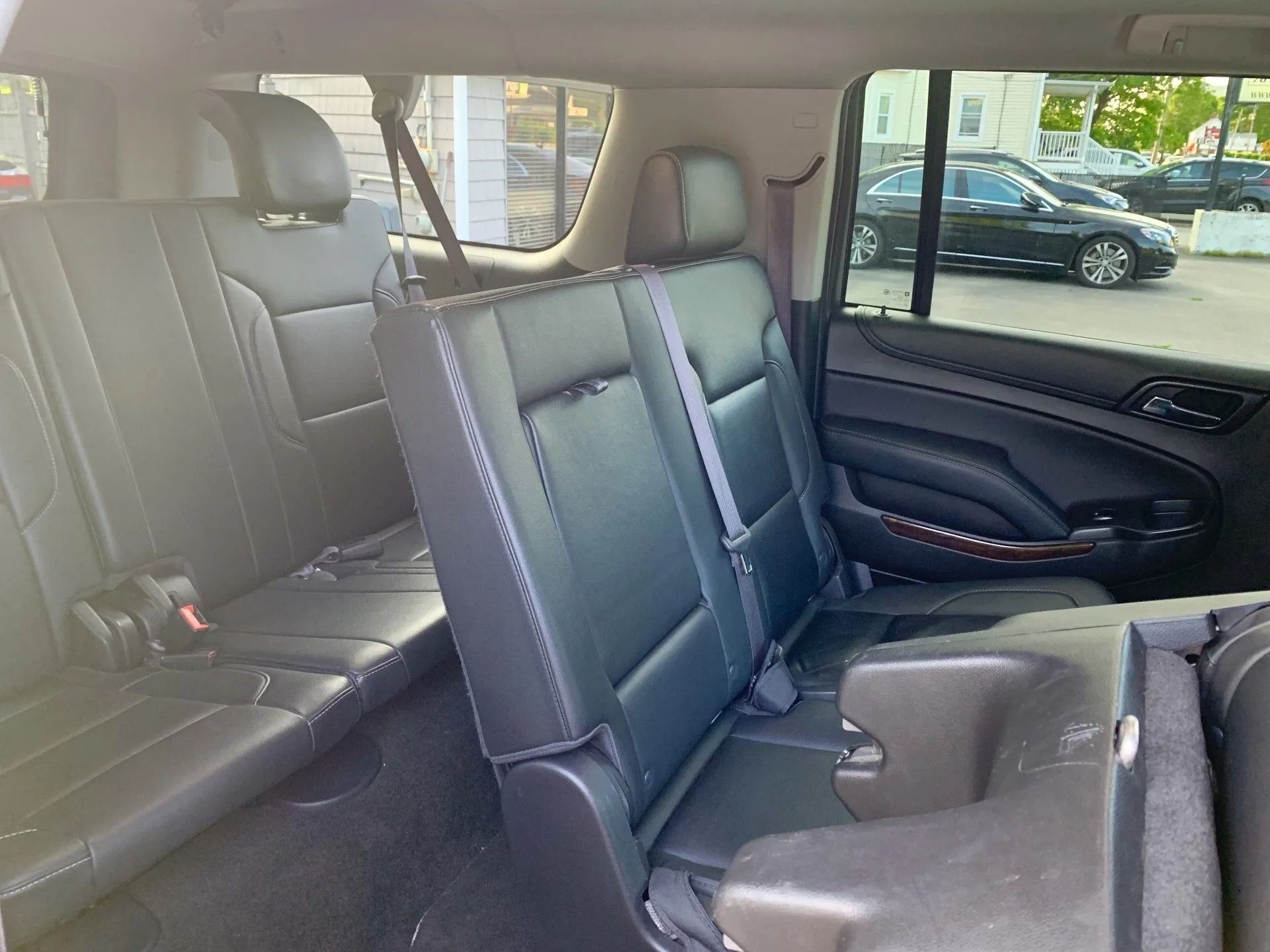 Interior view of a black SUV's second and third-row seats. The third row is folded up.