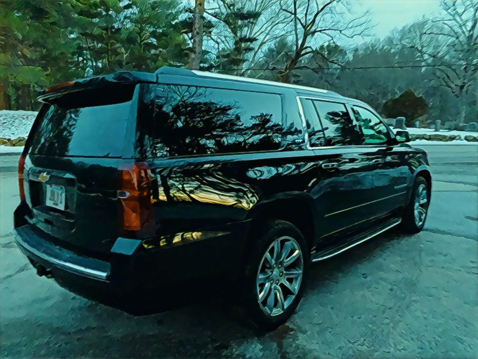 Black SUV parked outside on a paved surface, reflecting trees.