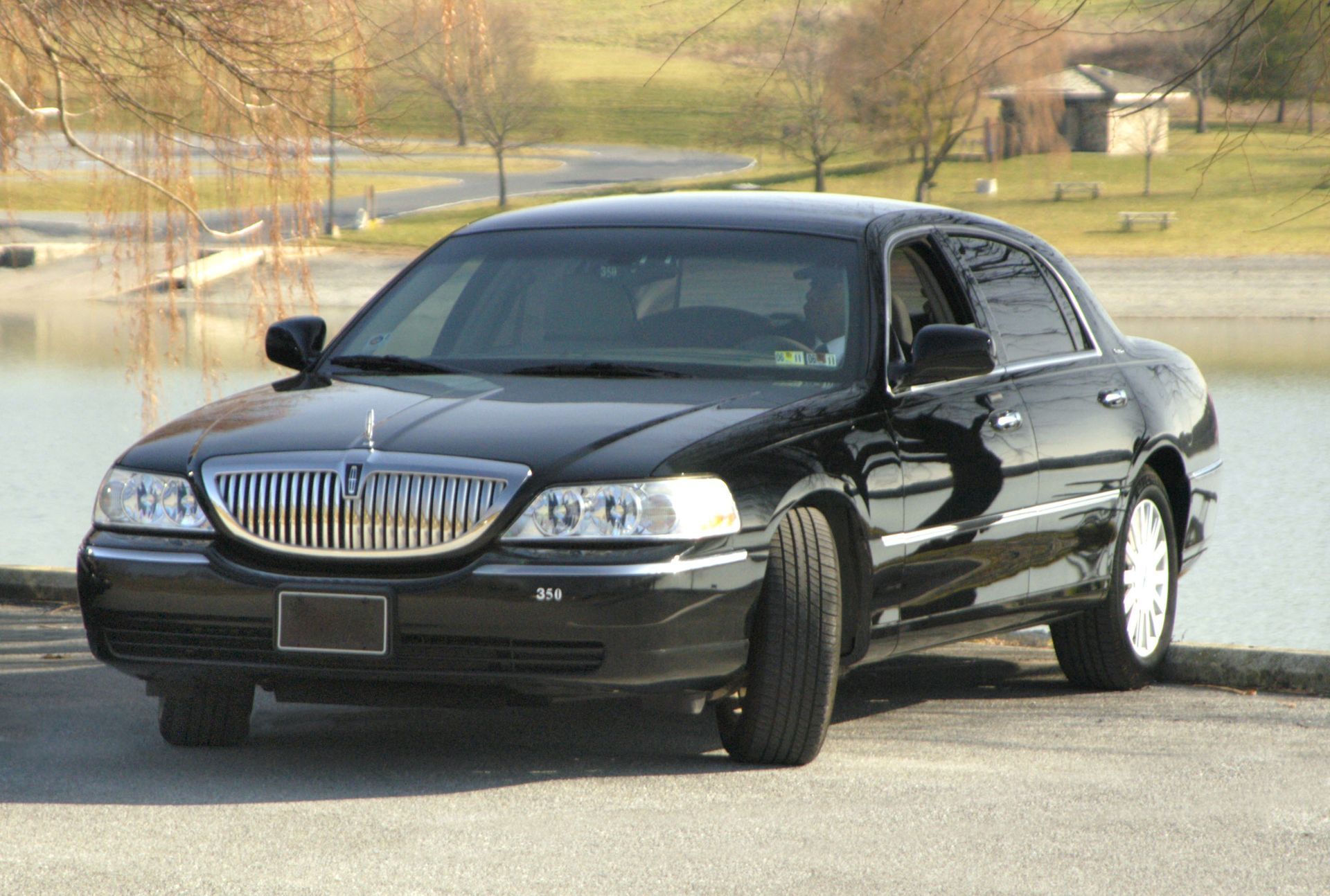 Black Lincoln Town Car parked near a lake, sunny day.