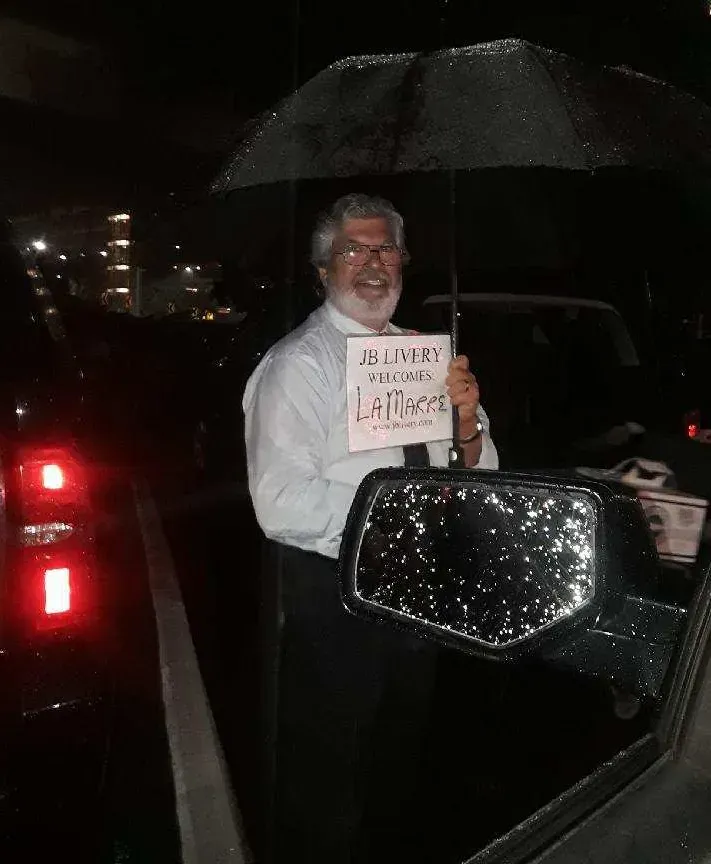 Man holding sign under umbrella at night.