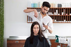 Stylist cutting the hair of his client inside a salon