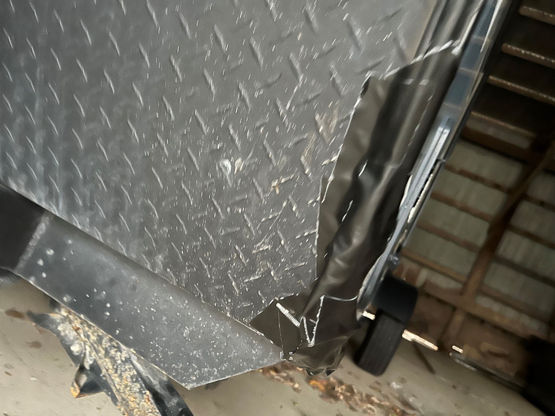 A black RV trailer with a broken side is sitting in a garage.