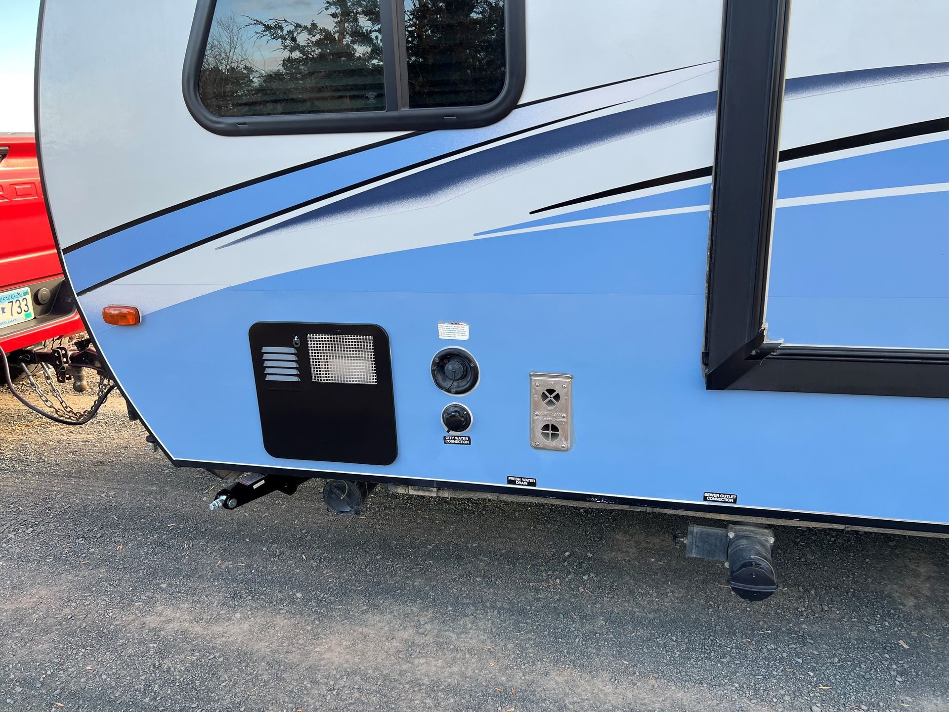 A blue and white RV is parked on the side of the road