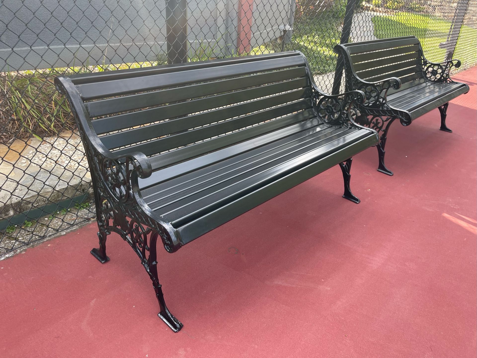 two black benches are sitting next to each other in a park