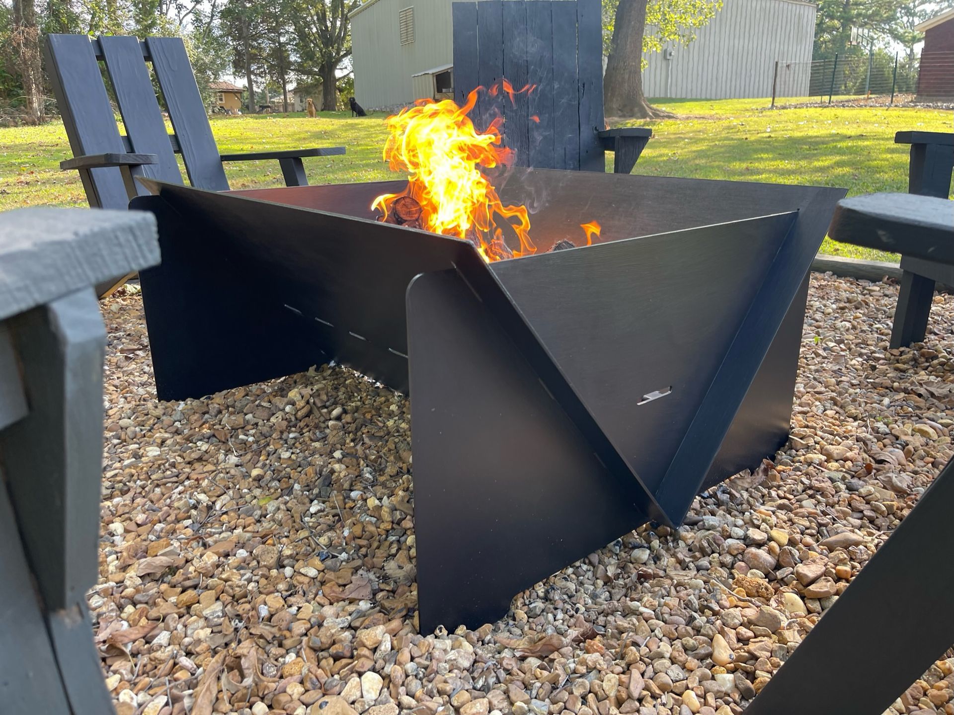 a fire pit is sitting on top of a pile of gravel next to chairs