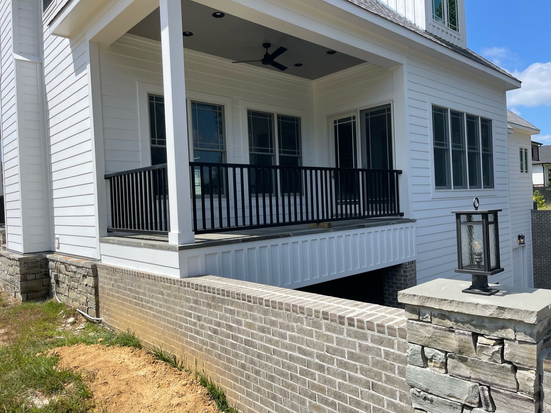 a white house with a balcony and a brick wall