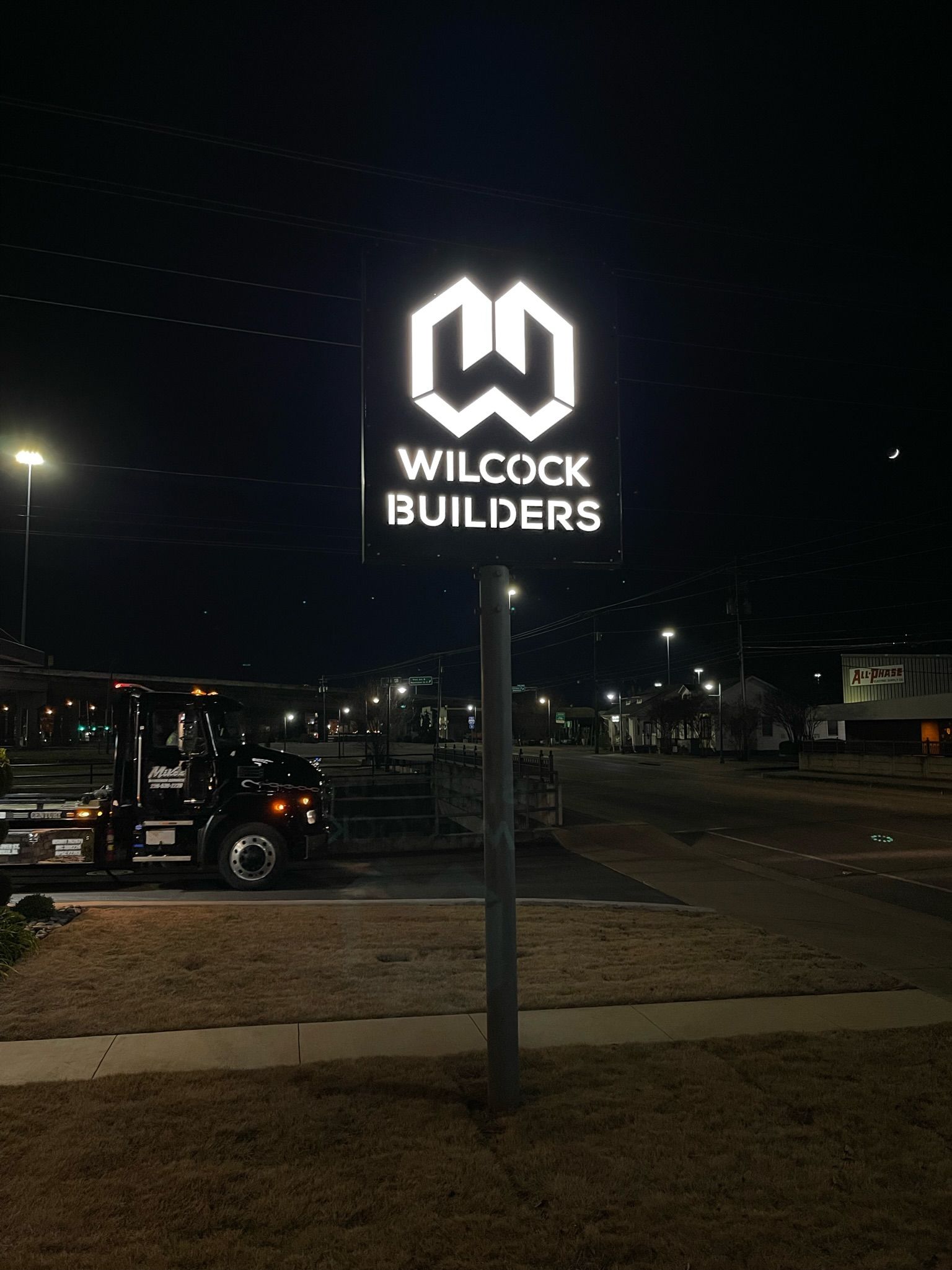 a sign for Wilcock Builders is lit up at night