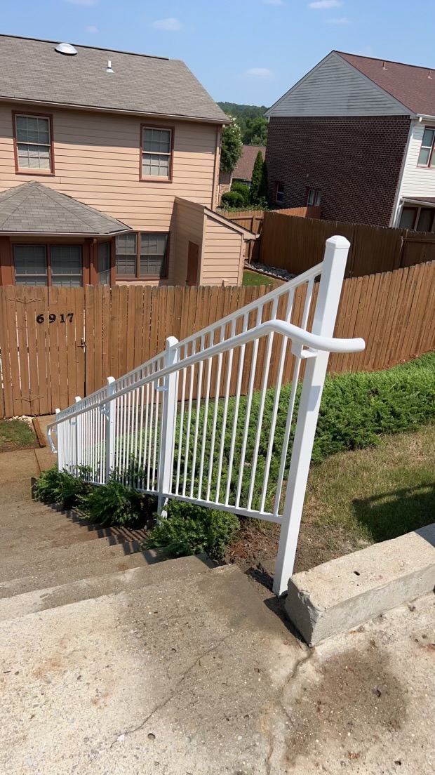 a white fence is leaning over a set of stairs in front of a house