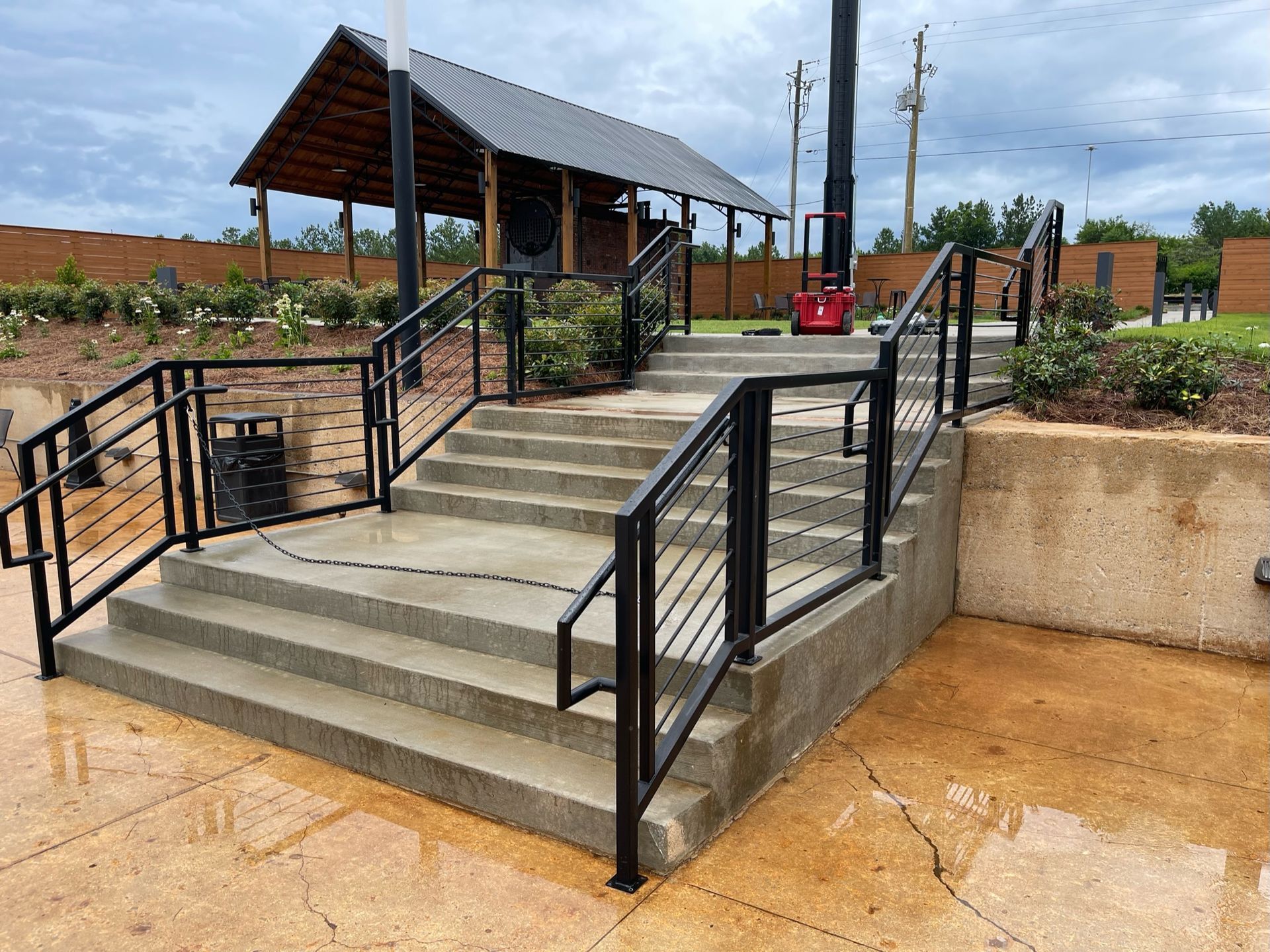 a set of stairs with a metal railing and a pavilion in the background