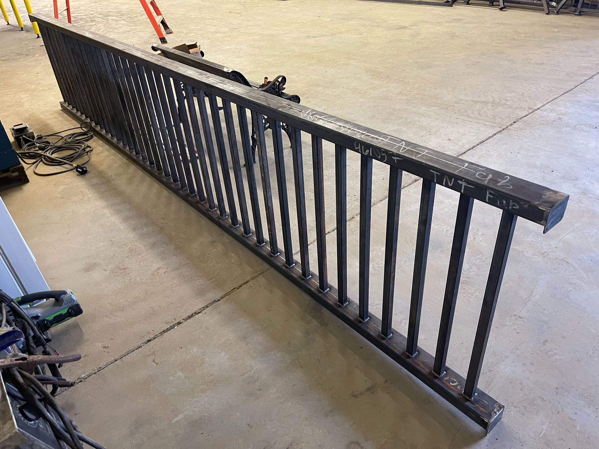a long metal railing is sitting on a concrete floor