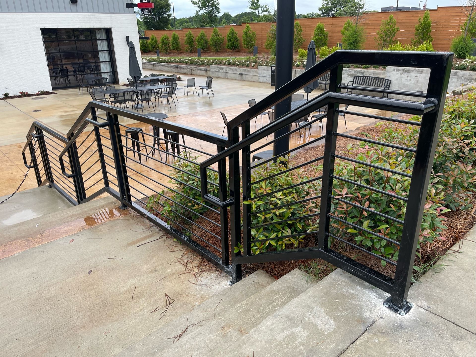 a black metal railing leading up to a patio with tables and chairs