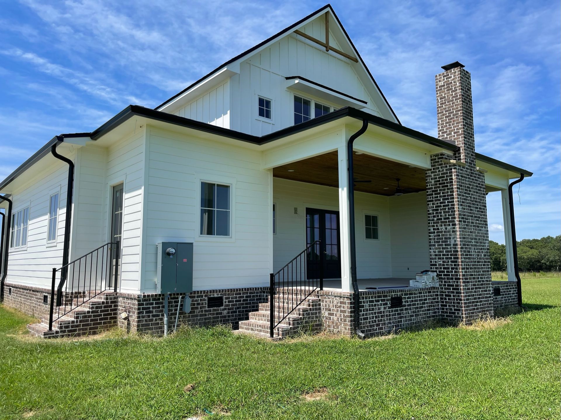 a white house with a stone chimney is sitting in the middle of a grassy field