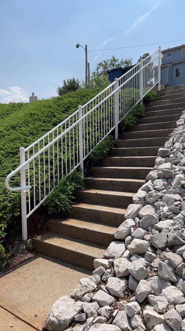 a set of stairs with a white railing going up a hill