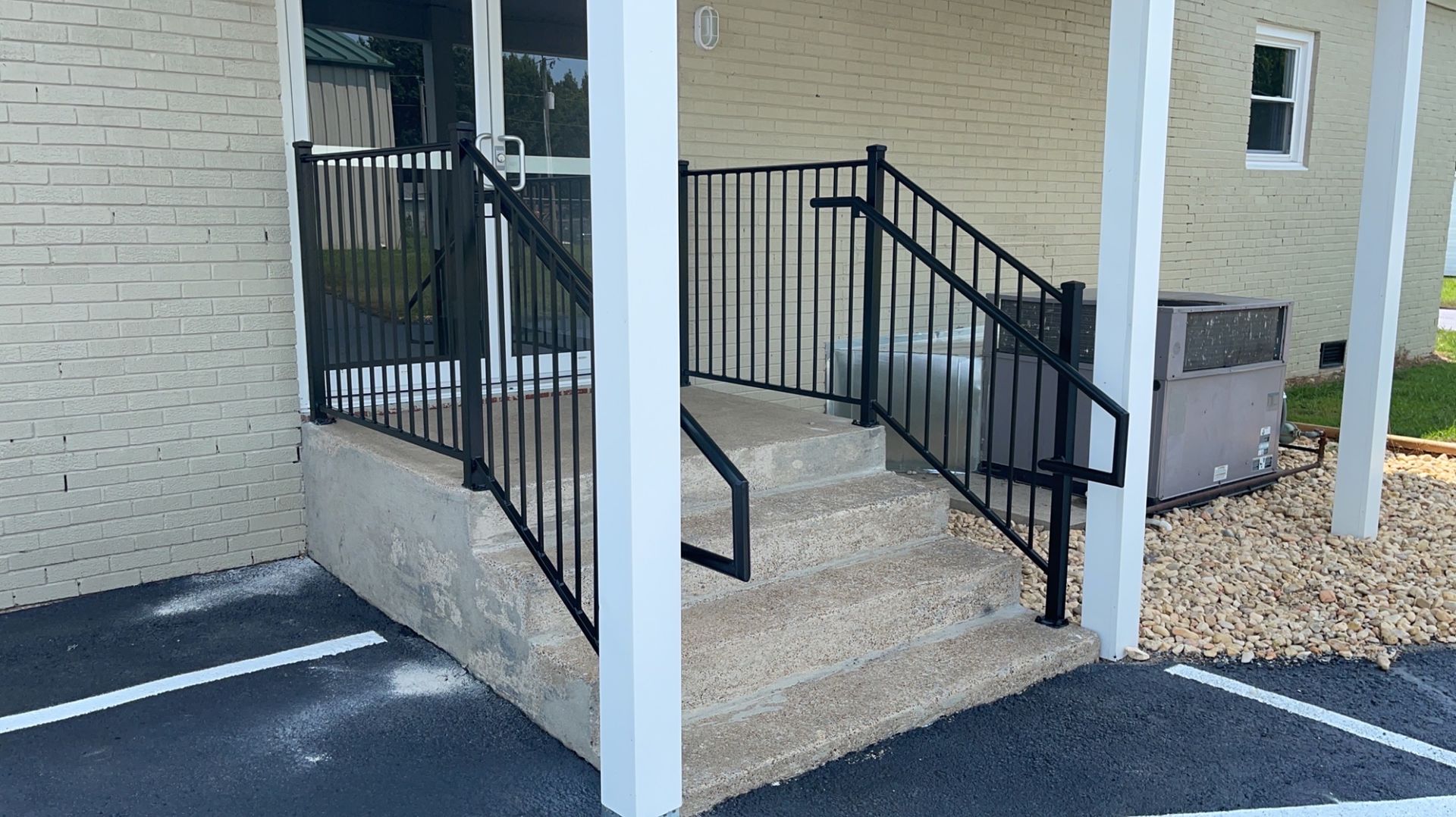 a white brick building with a black railing and stairs leading up to it
