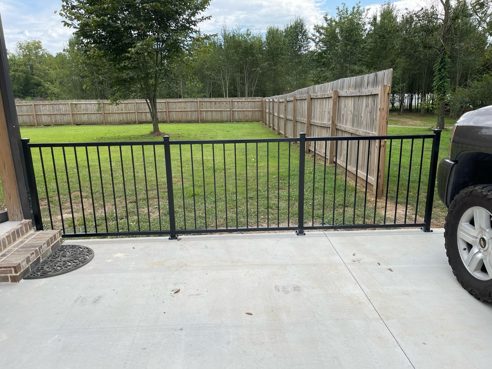 a car is parked in a driveway next to a fence
