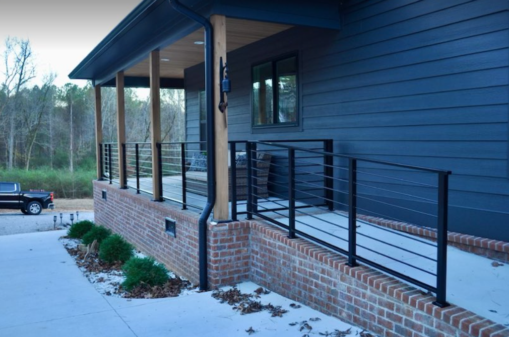 a black truck is parked in front of a blue house with a black railing