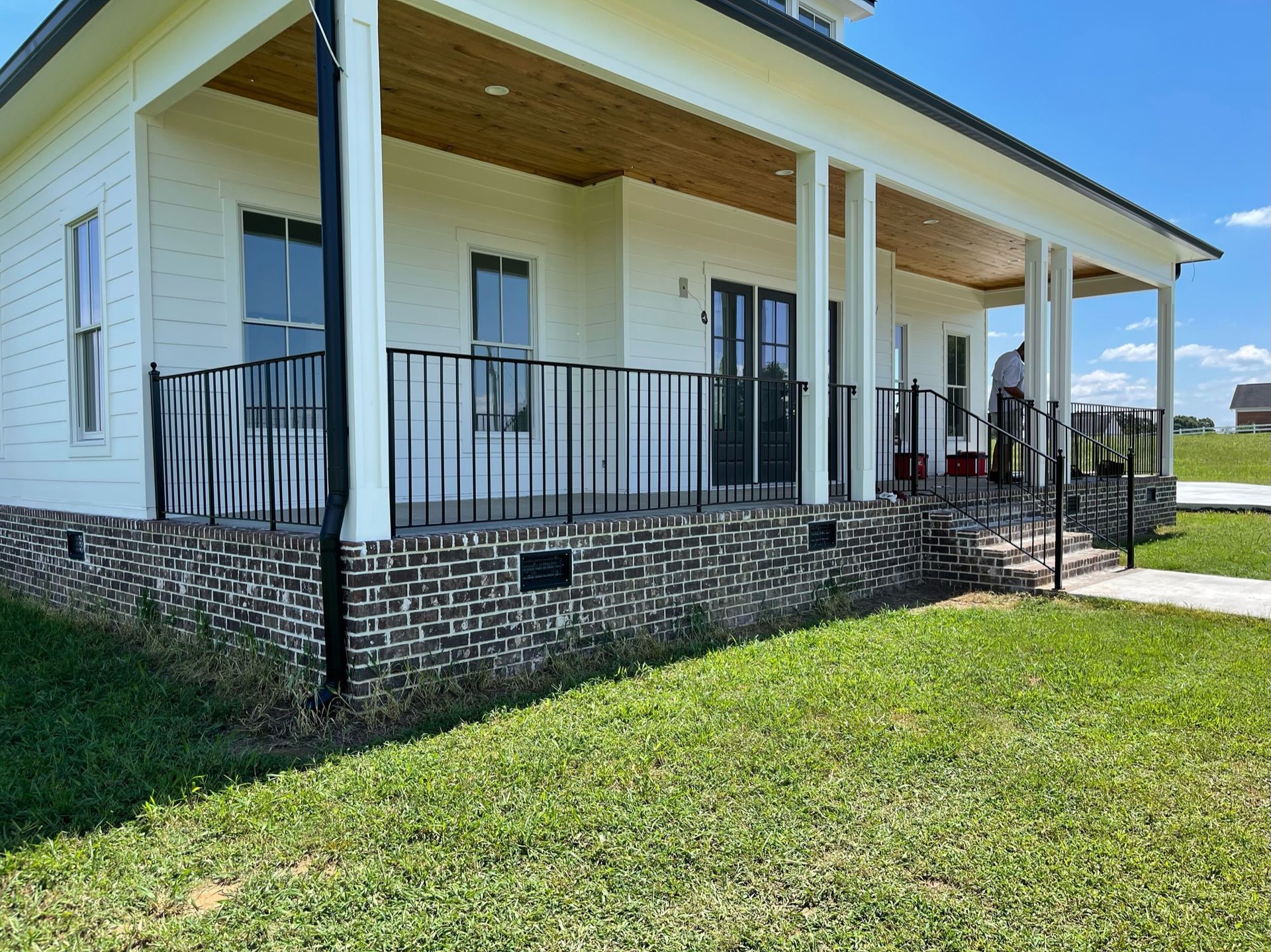 a white house with a large porch and a brick foundation