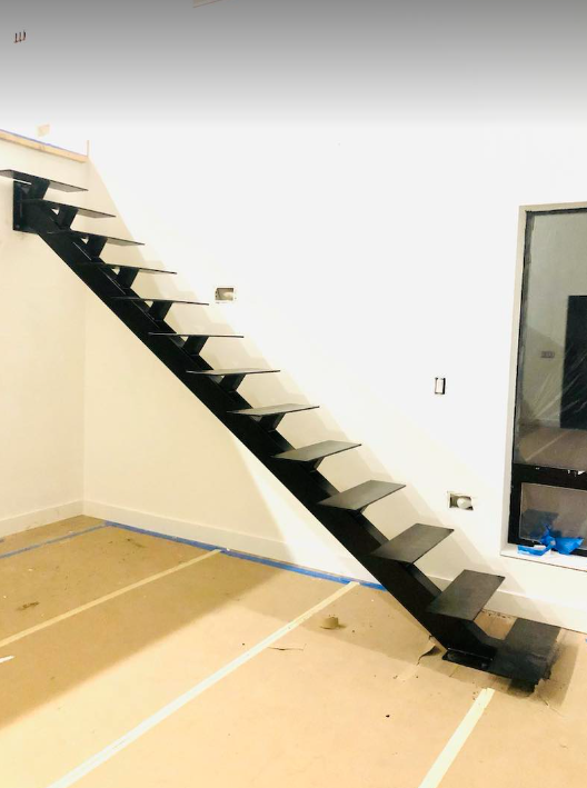 a black staircase in a room with a white wall