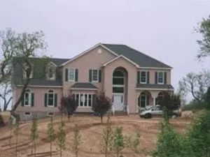 Beige two-story house with black roof, green shutters, and a white entrance. Car parked in front.